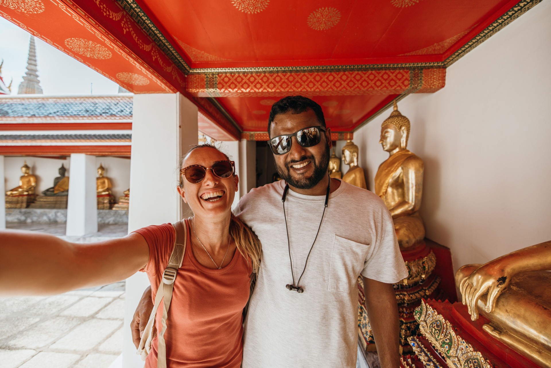 Tourists Smiling at a Buddhist Temple with Golden Statues